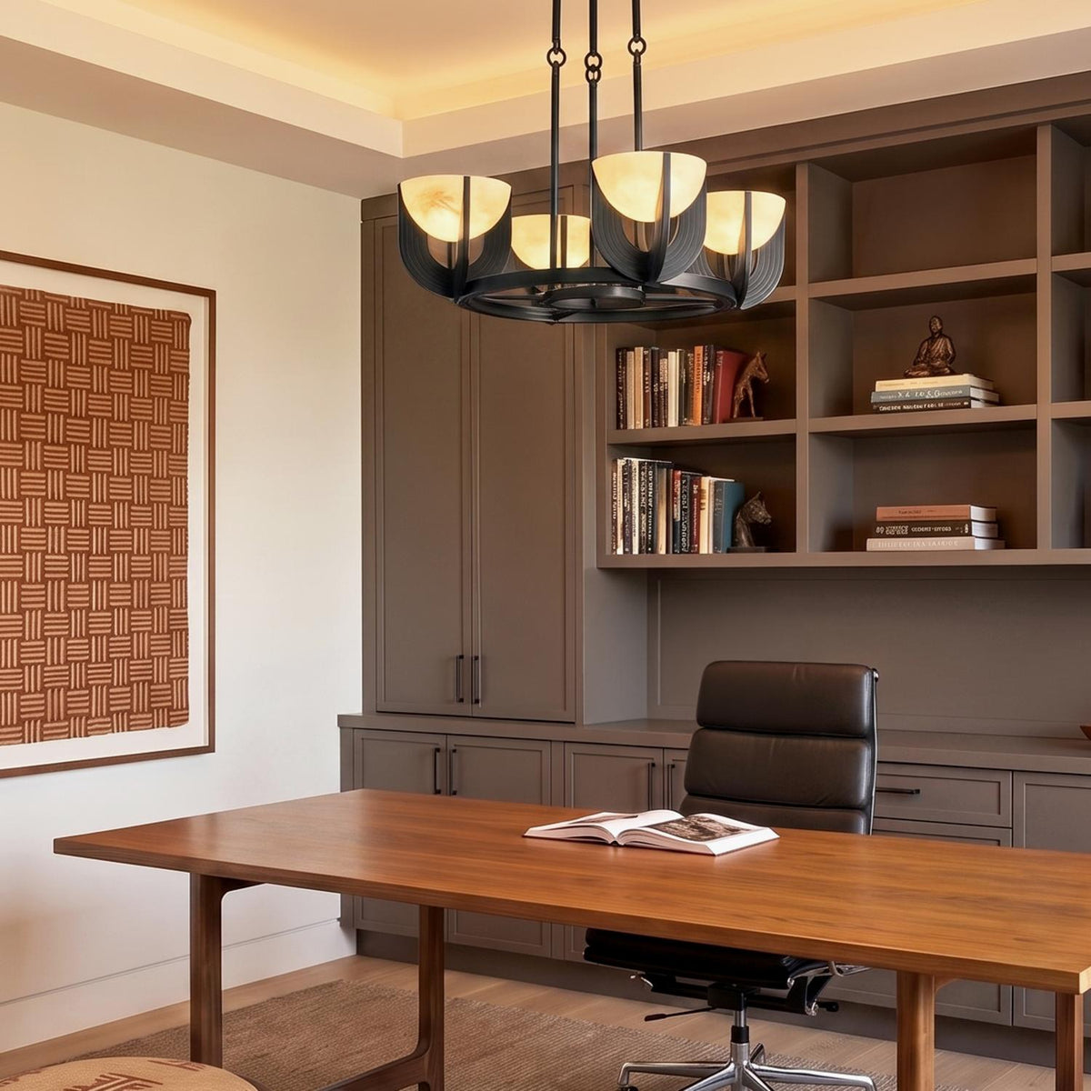 A transitional office featuring an urban bronze chandelier with glowing alabaster shades suspended over a walnut wood desk in front of taupe built-in bookshelves.