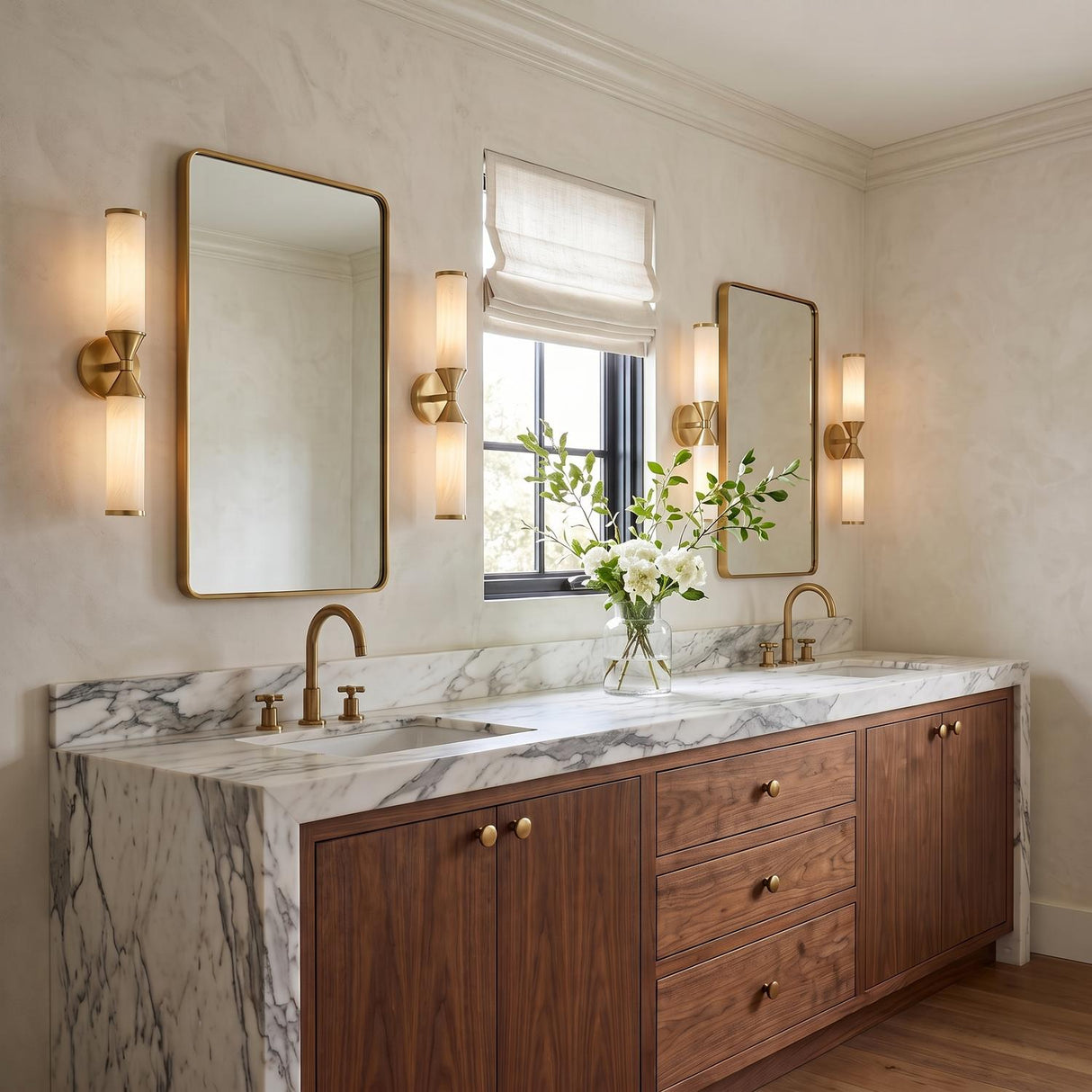 A transitional bathroom with aged brass and cloud glass wall sconces flanking two rectangular mirrors above a white marble double vanity featuring walnut wood cabinets.