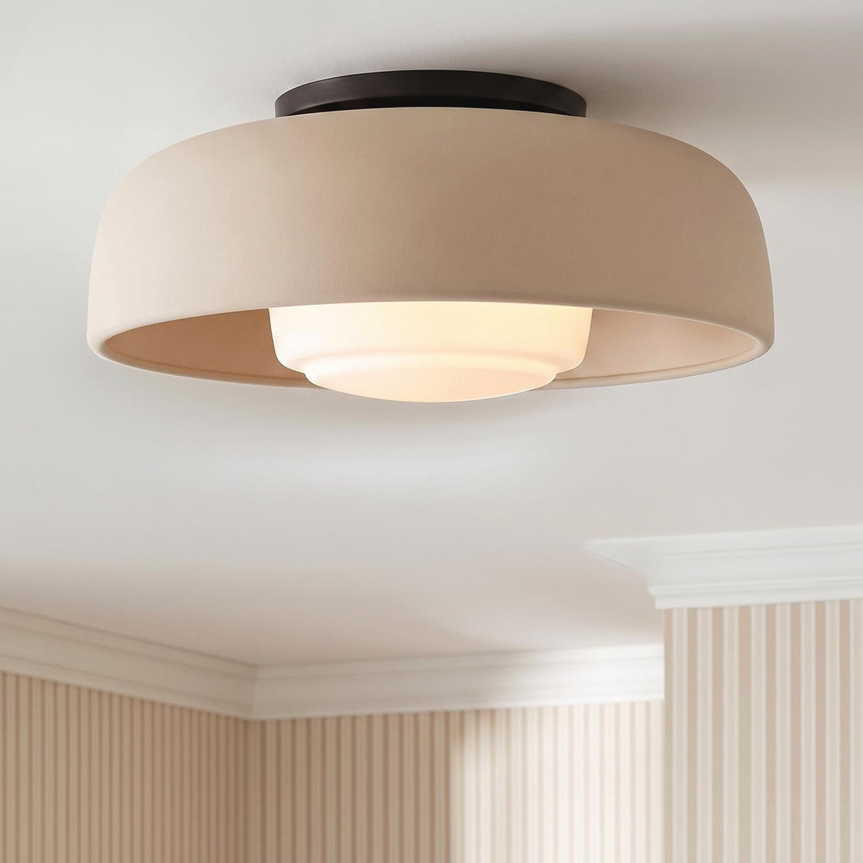 A transitional foyer featuring a Stratford Medium Flush Mount in aged iron and beige on a standard ceiling above beige striped wallpaper and white crown molding.