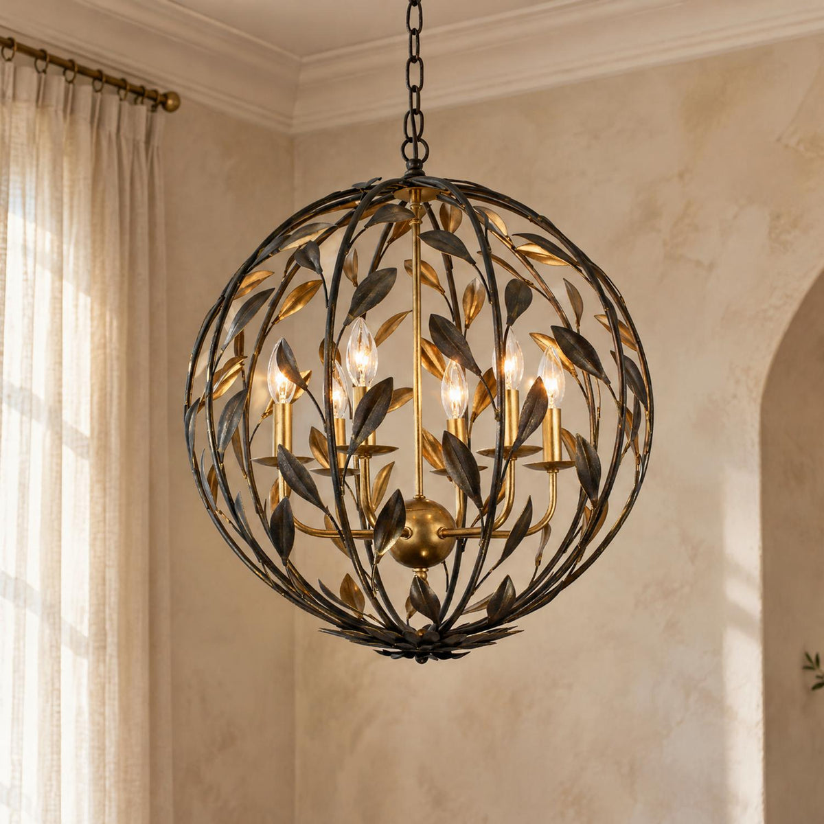 A transitional living room features the Alison Pendant 21-inch in Antique Bronze and Antique Gold hanging near textured beige walls, sheer curtains, and an arched doorway.
