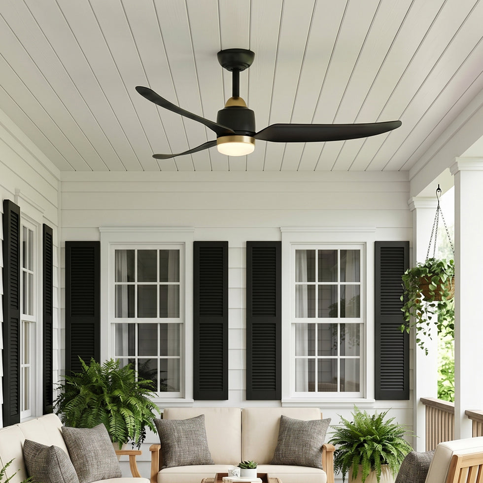Kent 52" LED Outdoor Rated Ceiling Fan Matte Black and Aged Brass finish shown on a front porch with white siding, black shutter, and hanging plants