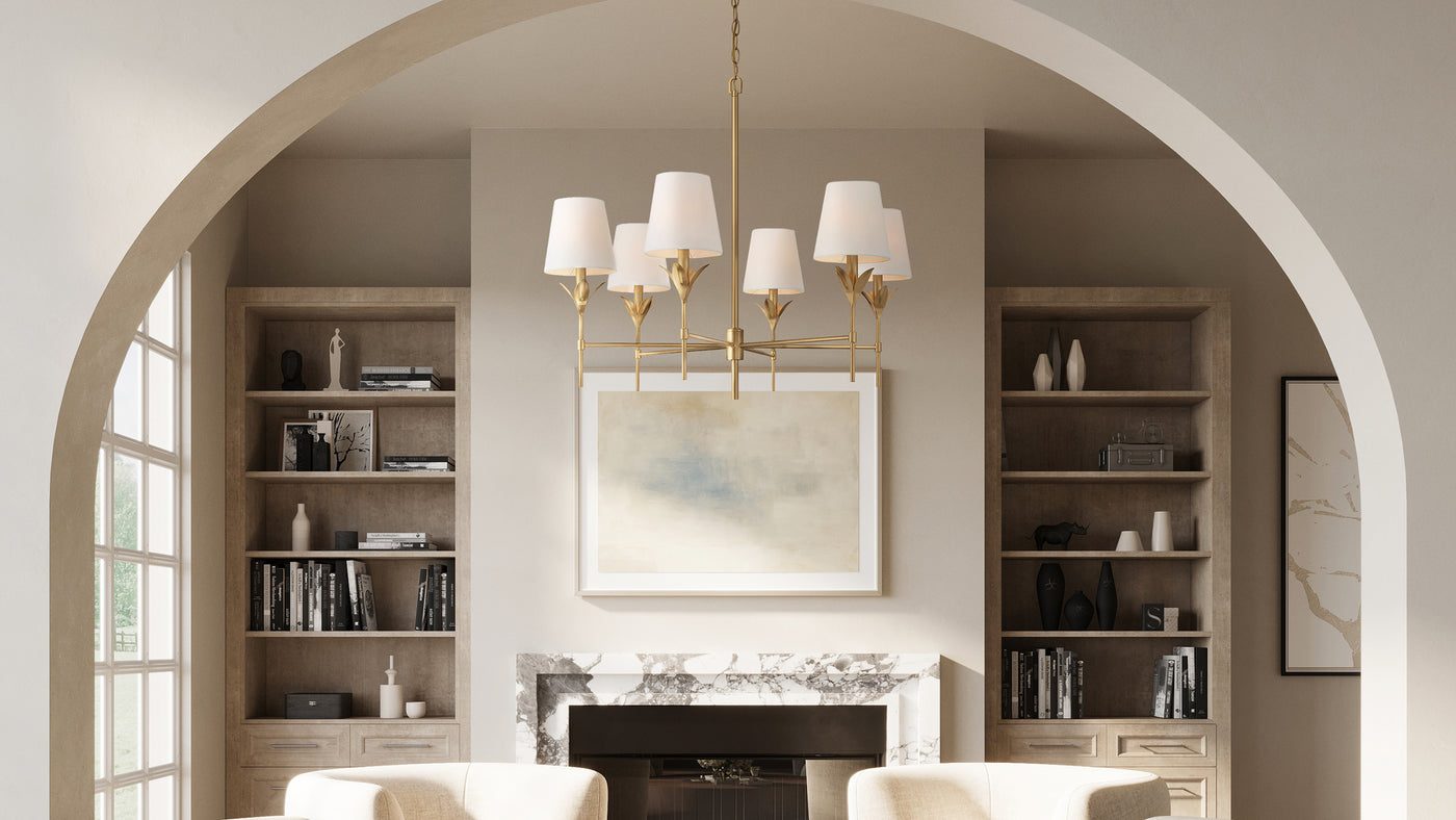 Alice 6 Light Chandelier in Antique Gold with white fabric shades is hung in a sitting room with an arched entryway and fireplace.