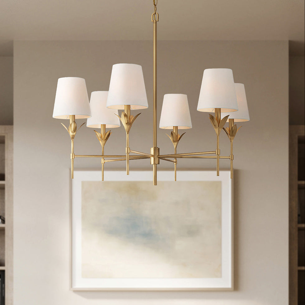 Alice 6 Light Chandelier in Antique Gold with white fabric shades is hung in a sitting room with an arched entryway and fireplace.
