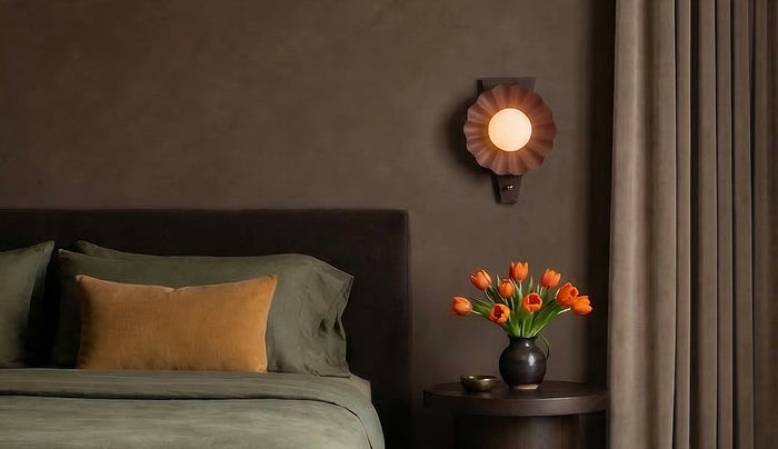Moody bedroom with the Babette Wall Sconce in Blush and Walnut wood, against a mink grey plaster wall and jewel tone bedding.