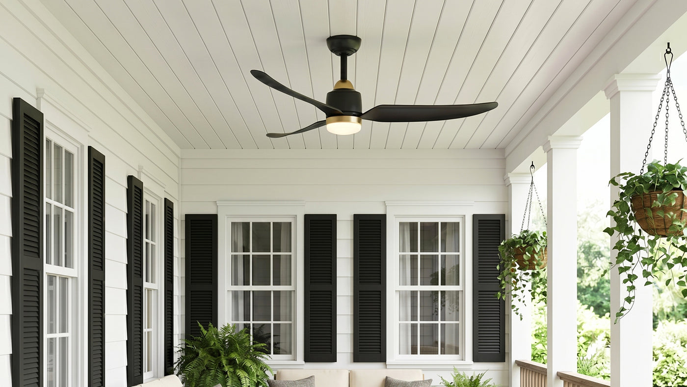 Kent 52" LED Outdoor Rated Ceiling Fan Matte Black and Aged Brass finish shown on a front porch with white siding, black shutter, and hanging plants