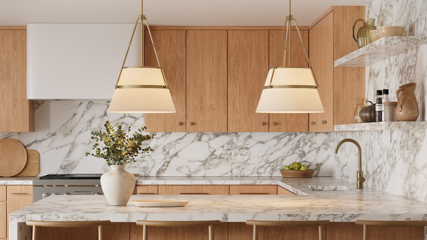 Two Julien Conical Pendant Lights in white and Aged Brass hung in a bright kitchen with white oaks cabinets and marble countertops.