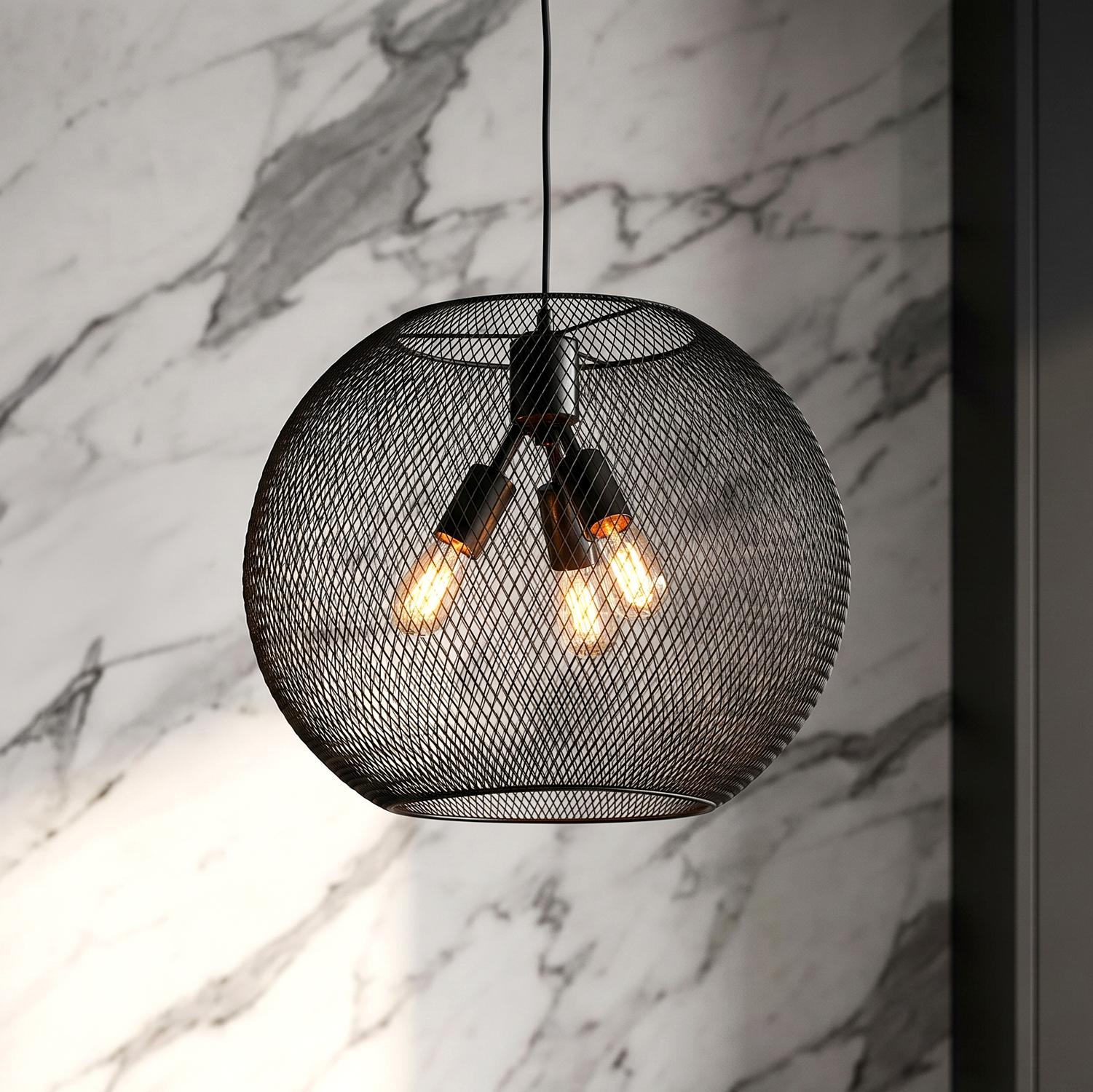 A modern kitchen with a matte black mesh globe pendant featuring three warm bulbs hanging along a white marble wall and dark cabinetry.