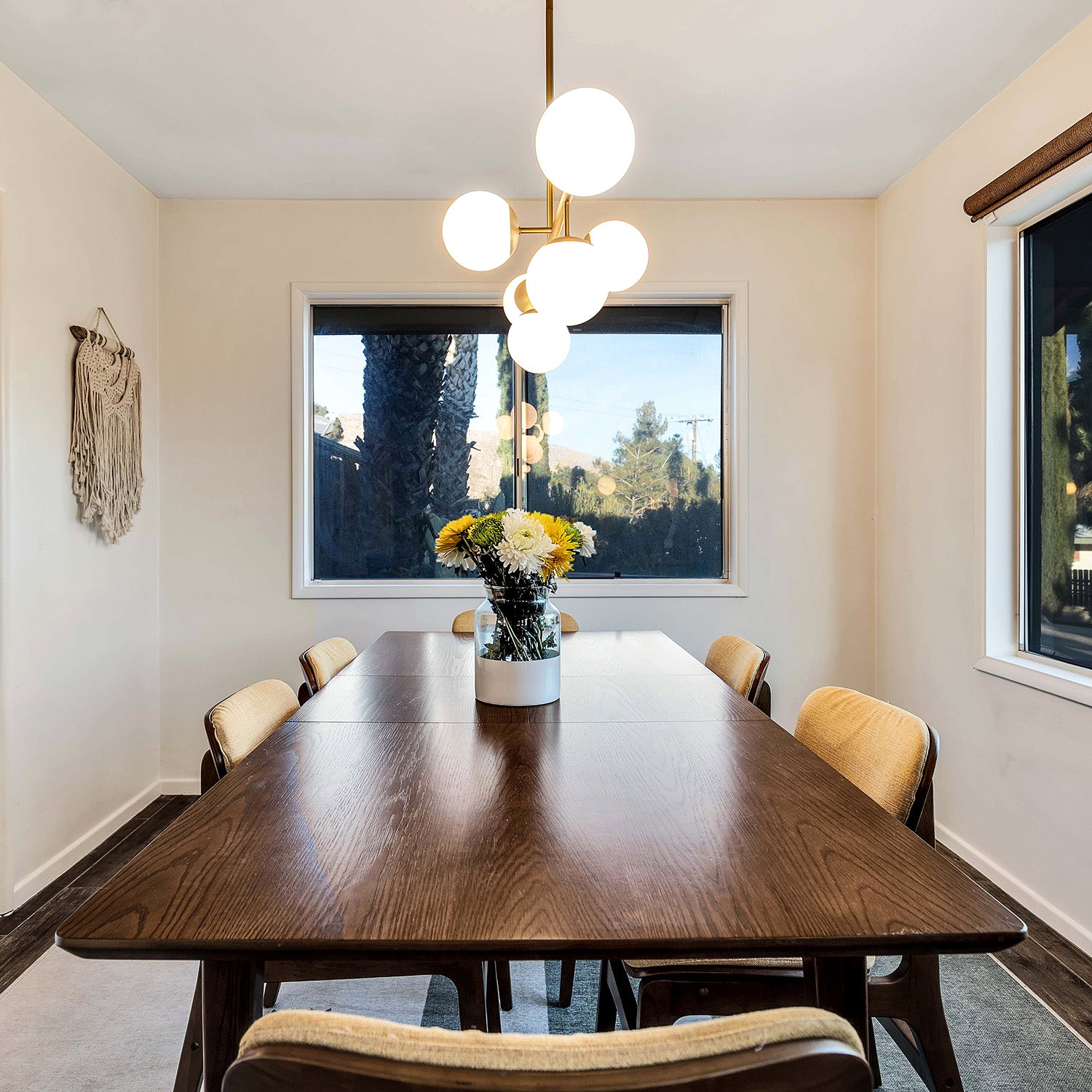 Castell 6 Globe Linear Mid-Century Modern LED Pendant, Aged Brass Finish with Opal White Glass Globes, in a customer's mid-century modern home above the dining table. Photo from Kit Williamson.