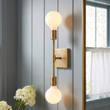 A modern farmhouse bathroom with an aged brass Prospect 2 Light Wall Sconce on light blue vertical shiplap walls beside a mirror and white hydrangeas.