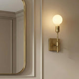 A transitional bathroom with the Prospect Wall Sconce, Aged Brass and an exposed globe bulb mounted next to a gold framed mirror on beige paneled walls.