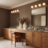 A contemporary bathroom with two Castell 4 Globe Vanity, Aged Brass fixtures mounted above rectangular mirrors, featuring light wood cabinets, marble countertops, and gold faucets.