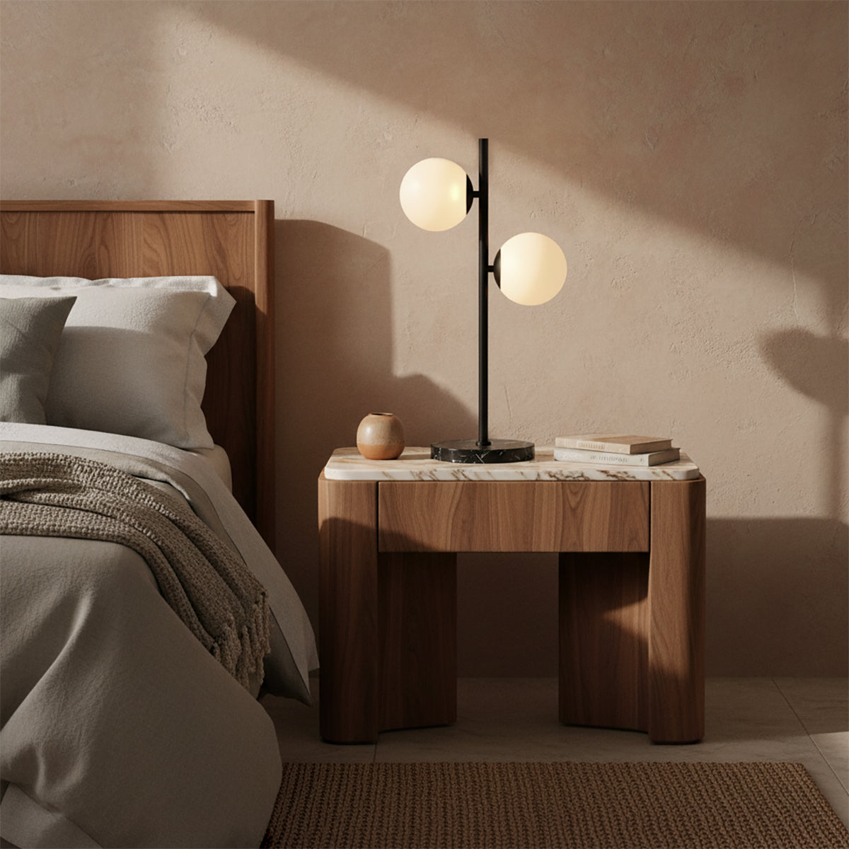 Castell 2 Globe Table Lamp, Matte Black - A modern table lamp with two white globes sits on a marble-topped nightstand next to a bed.