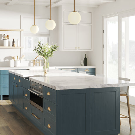 Three Castell LED 8" Globe Pendant Lights, Opal White Glass, Mid-Century Modern style, Aged Brass Metal Finish, in a blue and white kitchen