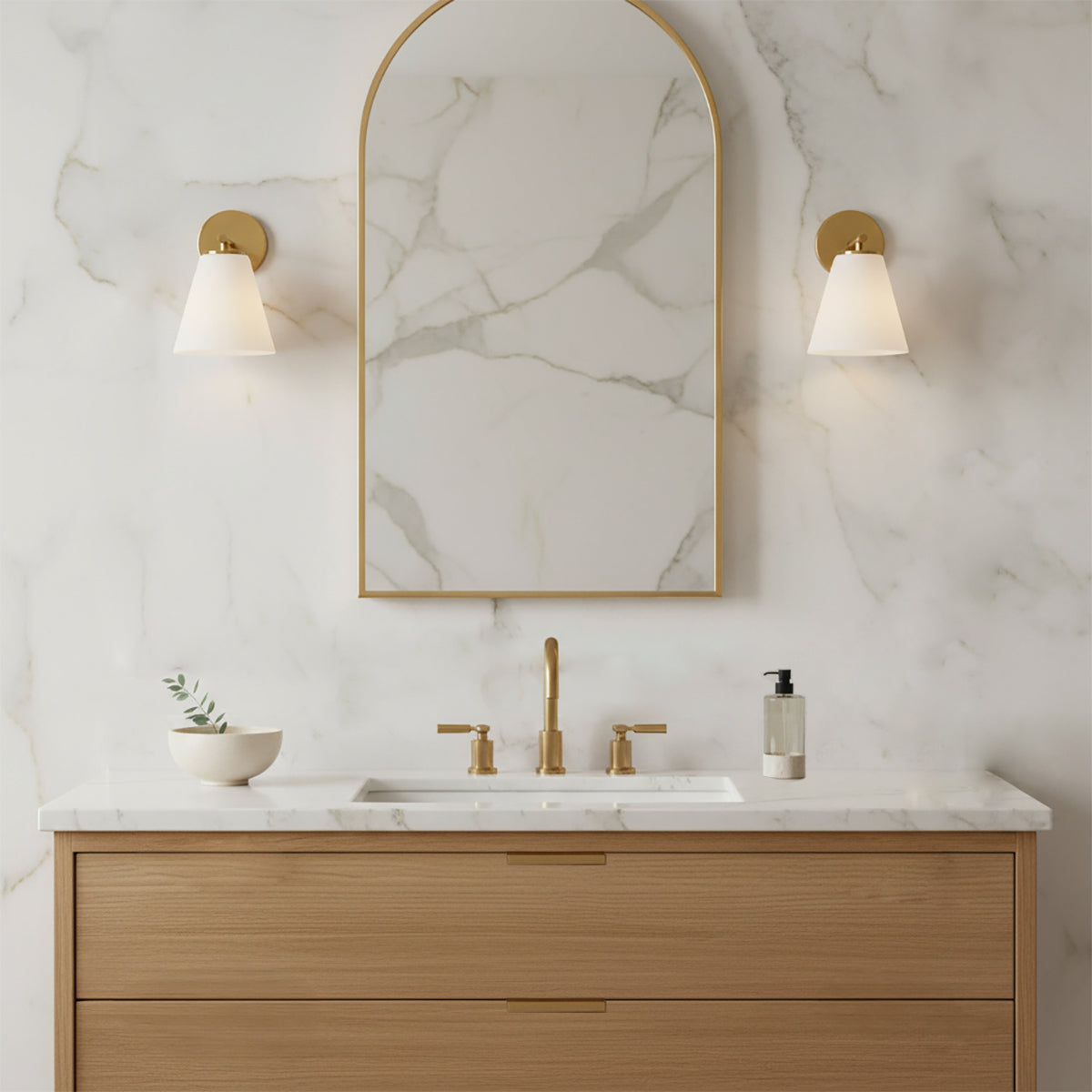 Carlisle Vanity Wall Sconce, Brushed Brass with Opal Glass - Bathroom vanity with two sconces and an arched mirror against a marble wall