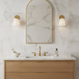 Carlisle Vanity Wall Sconce, Brushed Brass with Opal Glass - Bathroom vanity with two sconces and an arched mirror against a marble wall
