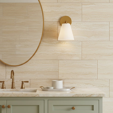 Carlisle Vanity Wall Sconce, Brushed Brass with Opal Glass shade - Vanity area with a brass wall sconce, gold-framed oval mirror, and sage green vanity cabinets.