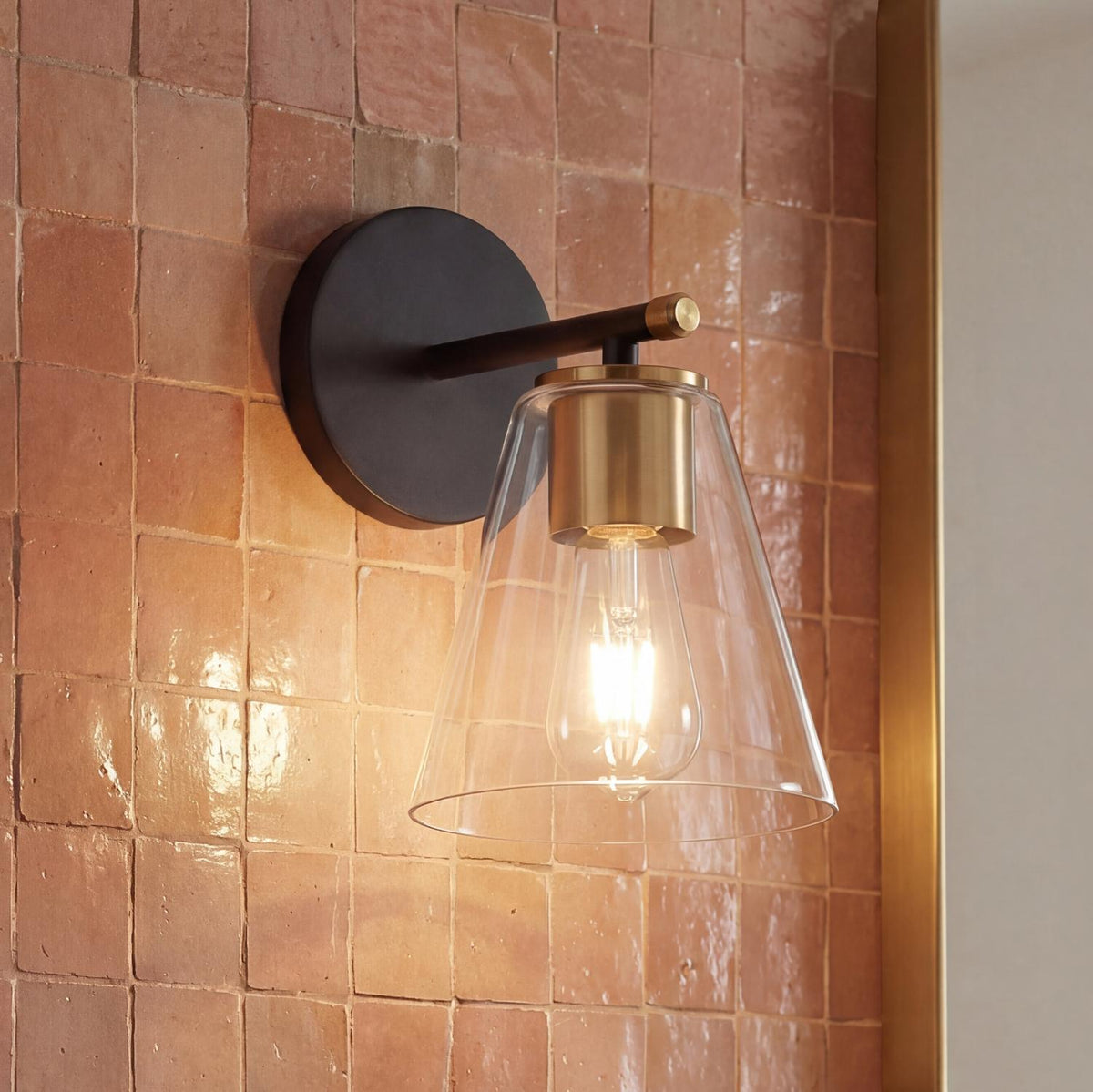 Carlisle Vanity Wall Sconce, Matte Black and Brushed Brass geometric wall sconce in a Transitional Bathroom with terracotta tiles.