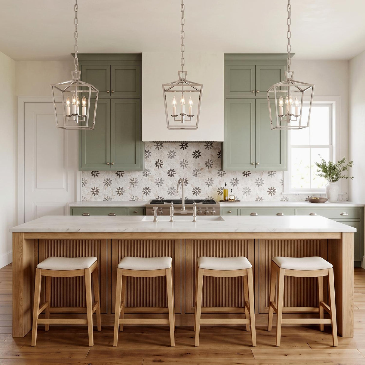 A transitional kitchen features three Anover Small Lantern Pendants in polished nickel over a light wood fluted island with sage green cabinets and floral backsplash.