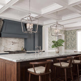 A transitional kitchen with two polished nickel lantern pendants over a white marble island with dark cabinetry under a white coffered ceiling.