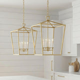 A farmhouse kitchen featuring two Anover Large Lantern Pendant 17-inch Satin Brass fixtures over the white island against white shiplap walls and shaker style cabinets.