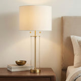 Laurel Glass Cylinder Table Lamp, Satin Brass geometric Table Lamp in a Transitional Bedroom with a dark wood nightstand.