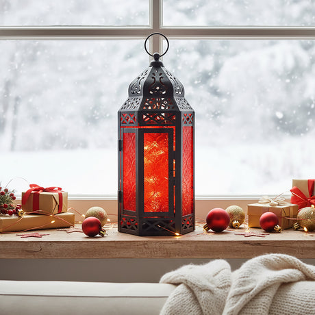 Red Glass Moroccan Christmas Lantern with twinkle lights for modern red and black holiday decor, shown in a winter window sill