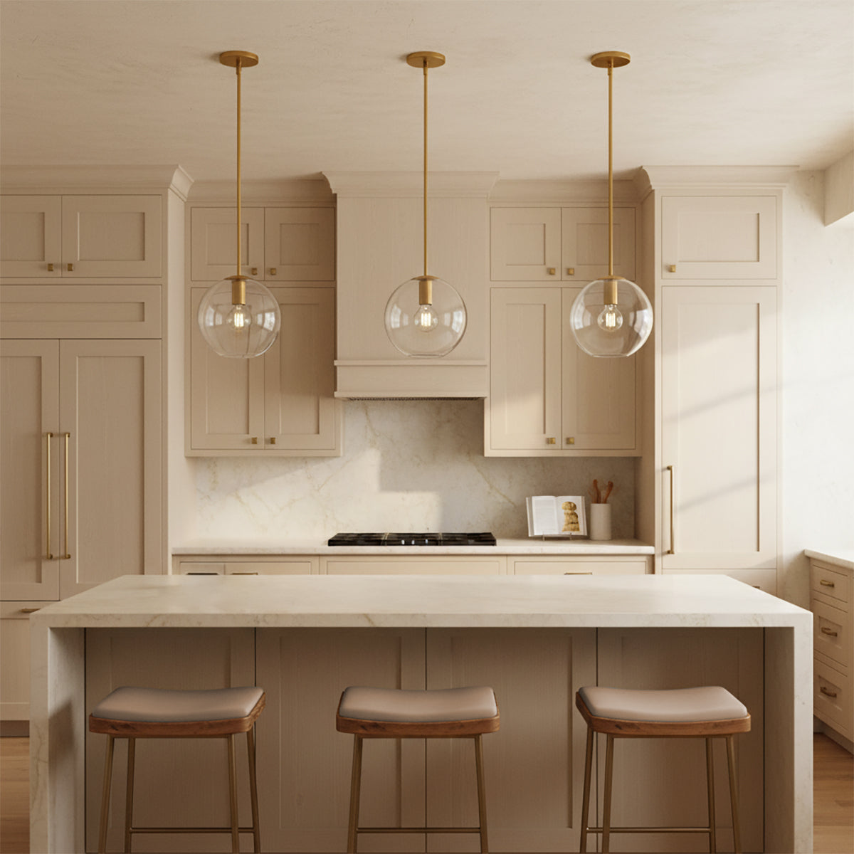Aria 10" Clear Globe Pendant, Satin Brass - Three clear glass pendant lights over a kitchen island in a warm earth-toned kitchen