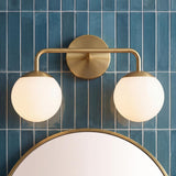 Castell 2 Globe Vanity Light, Aged Brass globe Vanity in a Contemporary Bathroom with blue subway tile and a round mirror.