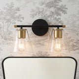 A transitional bathroom featuring the Carlisle 2 Light Vanity, Matte Black and Brushed Brass with Clear Glass mounted above a black framed mirror against gray toile wallpaper.