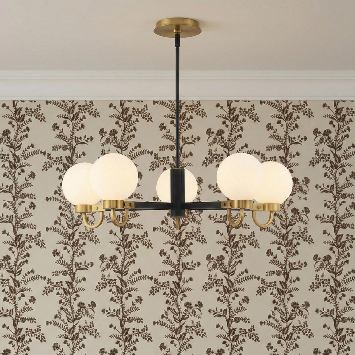 Arlo 5 Light Chandelier 30", Matte Black and Aged Brass globe Chandelier in a Transitional Dining Room with floral wallpaper.