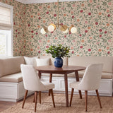 A cottage dining room featuring the Levi 4 Globe Chandelier in aged brass over a round mahogany table and cream banquette with botanical pomegranate wallpaper.