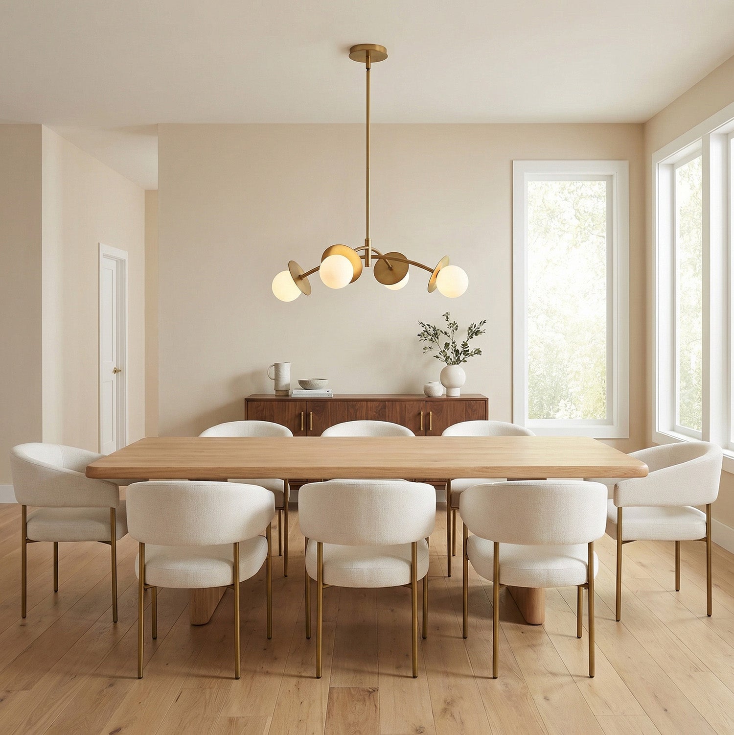 Aged Brass globe linear chandelier in a Transitional Dining Room with a light wood dining table and cream chairs.