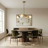 Levi 4 Globe Chandelier 26", Aged Brass globe chandelier in a Mid-Century Dining Room with a round walnut table and green velvet chairs.