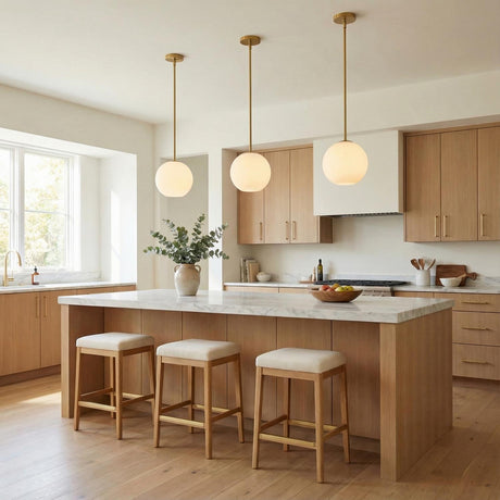 Aria 10" Opal Globe Pendant, Satin Brass globe Pendant in a Modern Kitchen with white marble island & light wood cabinets.