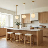 Aria 10" Opal Globe Pendant, Satin Brass globe Pendant in a Modern Kitchen with white marble island & light wood cabinets.