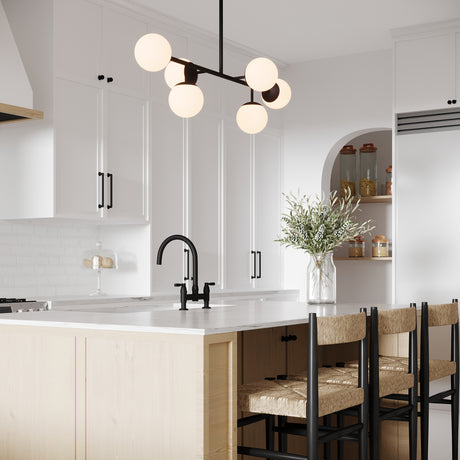 Castell 6 Globe Linear Mid-Century Modern LED Pendant, Matte Black Finish with Opal White Glass Globes, hung in a white kitchen above the island with black hardware and rattan counter stools.