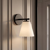 A transitional bathroom featuring a Carlisle Vanity Wall Sconce, Matte Black with Opal Glass mounted on a neutral paneled wall with decorative vertical molding details.