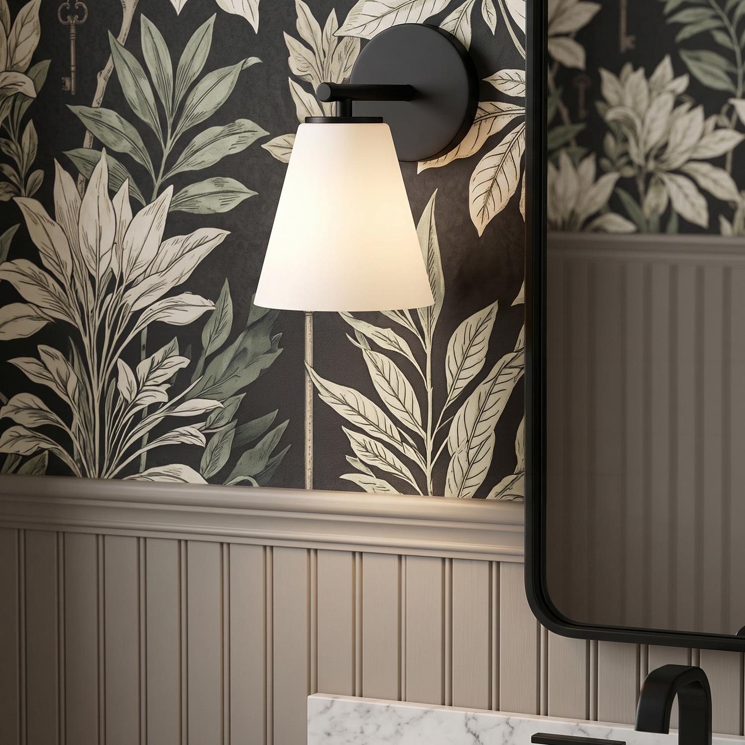 A transitional bathroom with a Carlisle Vanity Wall Sconce, Matte Black with Opal Glass, mounted above a marble counter and botanical print wallpaper with beadboard.
