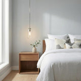 Liv 11" Clear Capsule Pendant, Polished Nickel capsule pendant in a Modern Bedroom with a wood nightstand and white bedding.