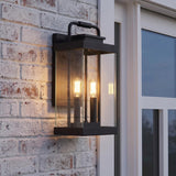 An outdoor entryway featuring the Parker Outdoor Wall Light, Large in a matte black finish with clear glass panels mounted on a whitewashed brick wall.