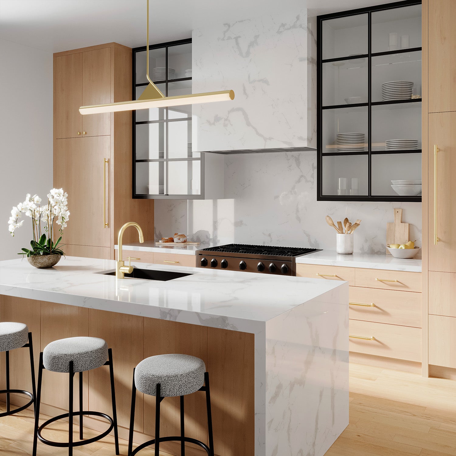 Modern kitchen featuring a white marble island and backsplash, blonde wood cabinetry, black and satin brass details, and illuminated by a sophisticated modern 45