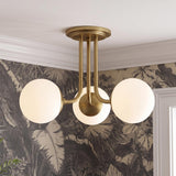 A mid-century foyer with the Castell 3 Globe Semi-Flush 20 inch Aged Brass fixture featuring frosted glass globes against tropical leaf pattern wallpaper and white crown molding.