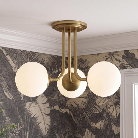A mid-century foyer with the Castell 3 Globe Semi-Flush 20 inch Aged Brass fixture featuring frosted glass globes against tropical leaf pattern wallpaper and white crown molding.