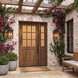 A Mediterranean home entry featuring two matte black Preston Outdoor Wall Light, Medium lanterns flanking a walnut door on white-washed brick with flowering bougainvillea vines at dusk.