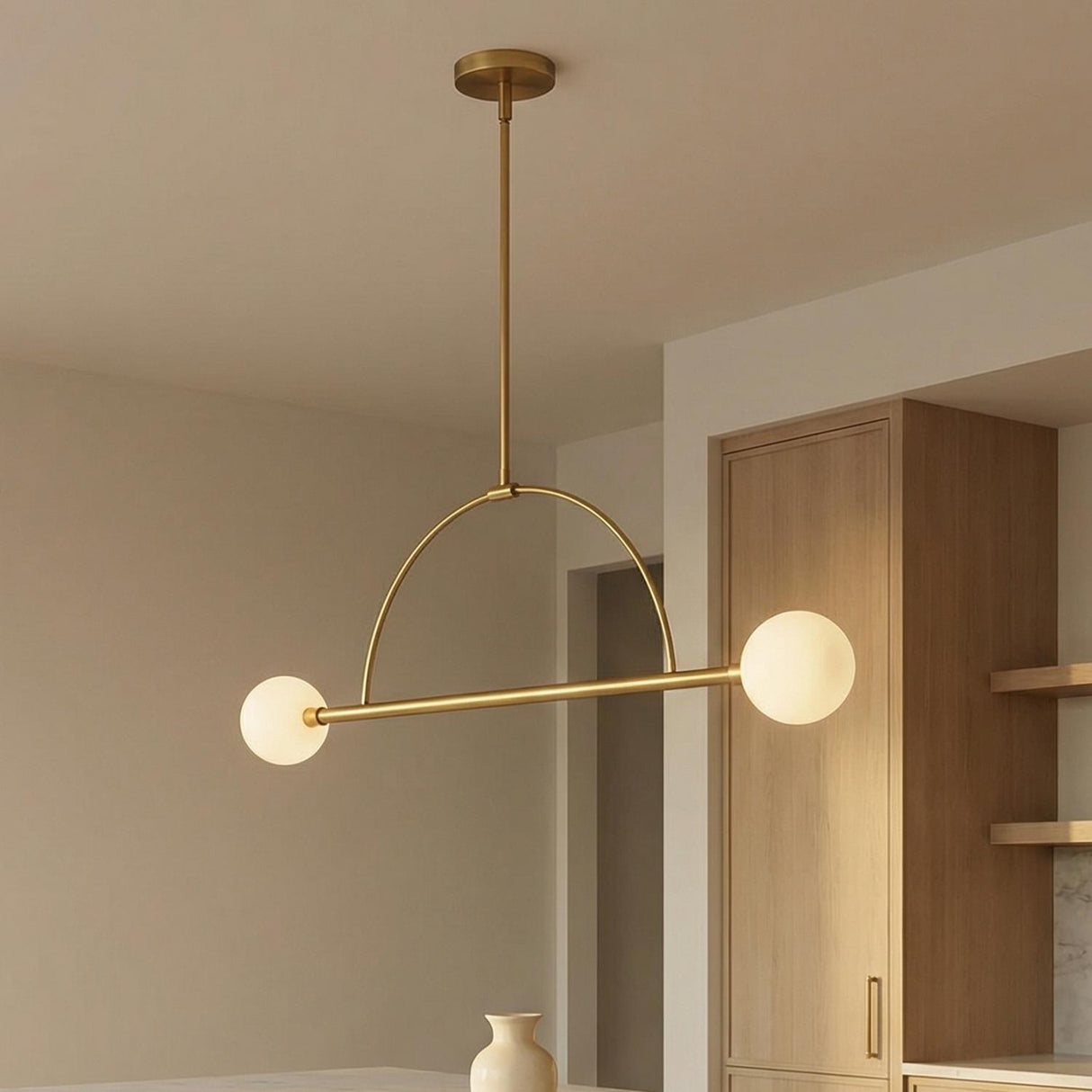 Milo 2 Globe Linear Arc Pendant 39", Aged Brass globe linear arc Pendant in a Mid-Century Kitchen with a white marble island.