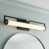A contemporary bathroom featuring the Ian LED Vanity Light, Matte Black and Chrome, mounted over a round mirror against light blue vertical tile with crown molding.
