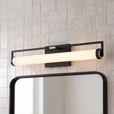A contemporary bathroom with the Ian LED Vanity Light, Matte Black and Chrome, mounted above a black framed mirror on a textured white square tile wall.