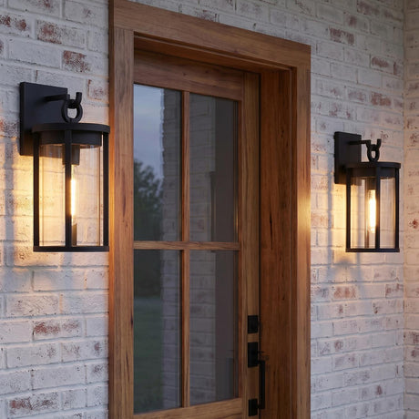 A modern farmhouse entryway with two matte black Cyrus Outdoor Wall Light, Medium lanterns flanking a natural wood front door on a white-washed brick wall.