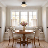 A cottage dining nook with the Jayden Flush Mount 14", Matte Black on the ceiling over a round wood pedestal table and built-in window seat with shiplap walls.