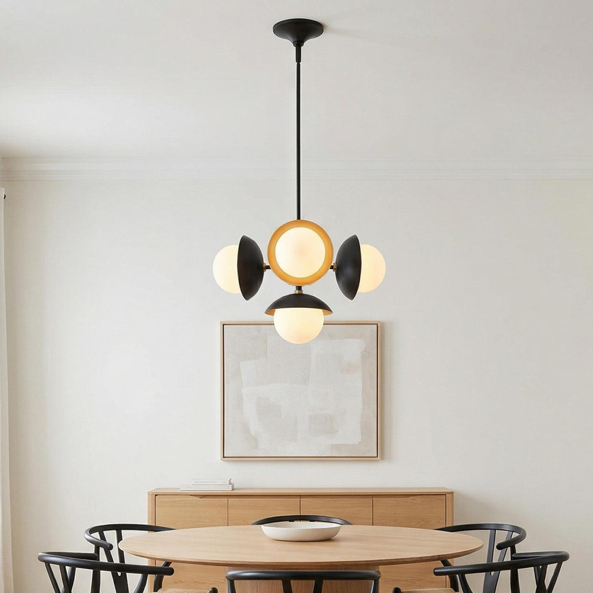 Luna Matte Black and Gold globe pendant in a Mid-Century Dining Room with a round oak table and black wishbone chairs.